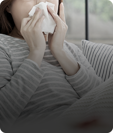 Person with allergy symptoms holding a tissue
